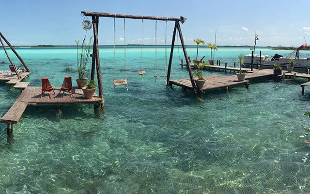 Wood swings at Bacalar beach. One of the destinations available for Cancun Airport Transportation